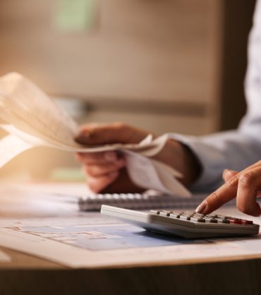 closeup-economist-using-calculator-while-going-through-bills-taxes-office (1)