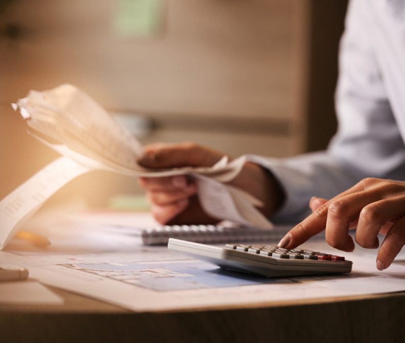 closeup-economist-using-calculator-while-going-through-bills-taxes-office (1)