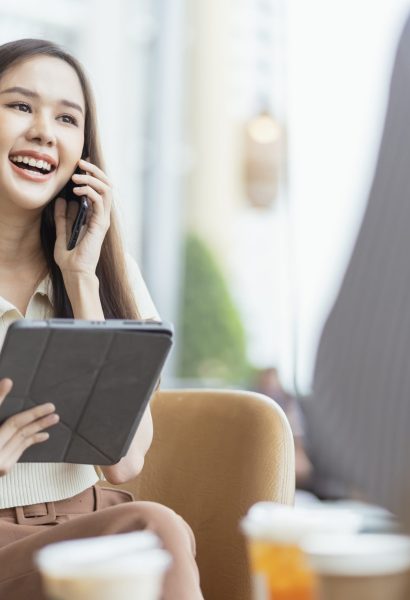 relax leisure attractive smart asian female freelance entrepreneur smile and enjoy working with smartphone and laptop at cafe with blur city business digital nomad remotely work casual ideas concept