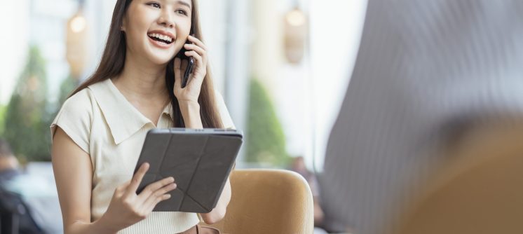 relax leisure attractive smart asian female freelance entrepreneur smile and enjoy working with smartphone and laptop at cafe with blur city business digital nomad remotely work casual ideas concept