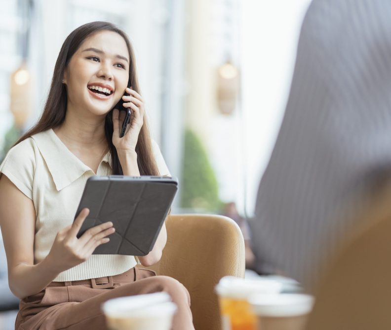 relax leisure attractive smart asian female freelance entrepreneur smile and enjoy working with smartphone and laptop at cafe with blur city business digital nomad remotely work casual ideas concept