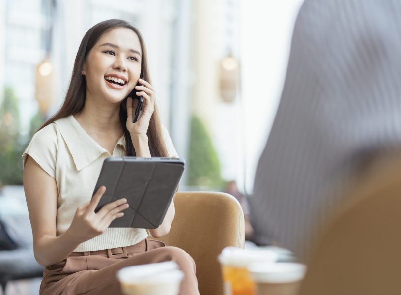 relax leisure attractive smart asian female freelance entrepreneur smile and enjoy working with smartphone and laptop at cafe with blur city business digital nomad remotely work casual ideas concept